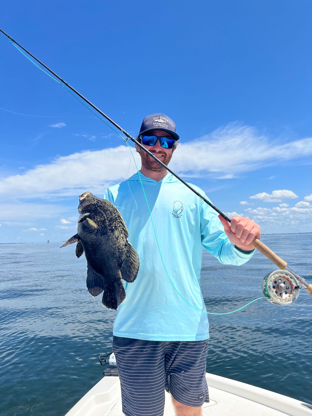 Angler holding a hogfish with a fly rod on a nearshore charter