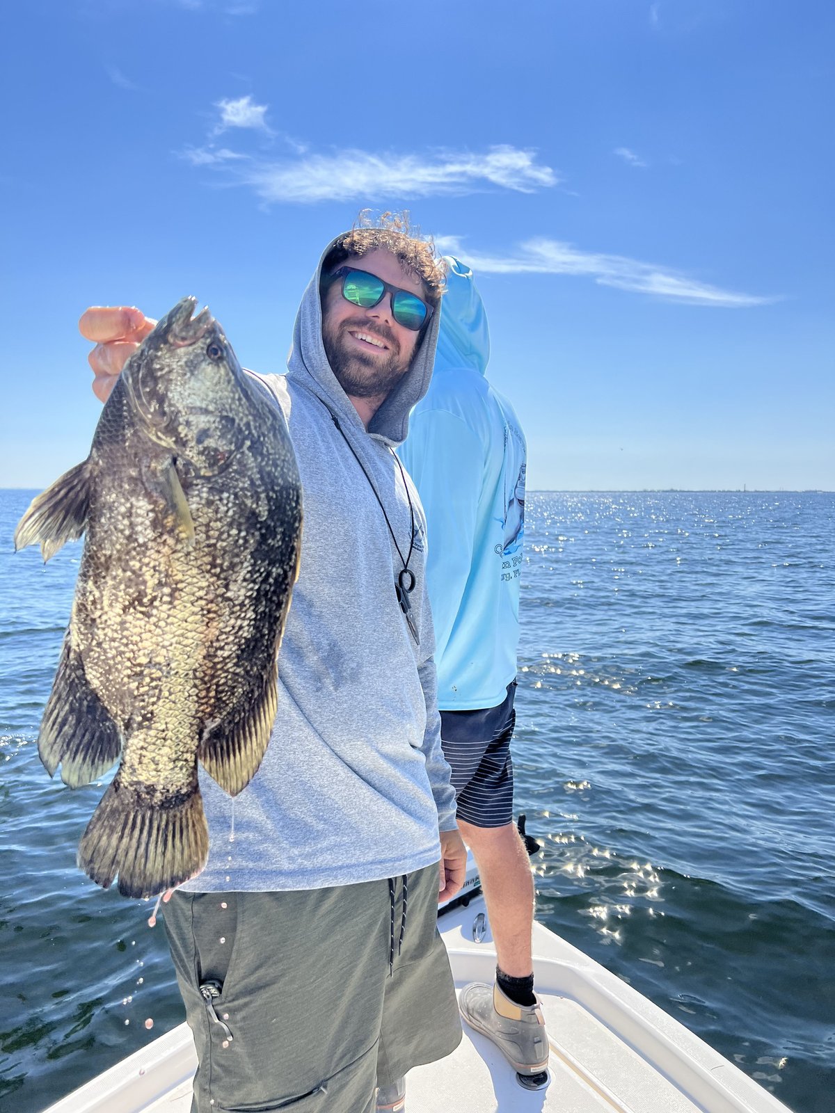 A guest holding a heavy grouper on the bow of the Next Catch boat