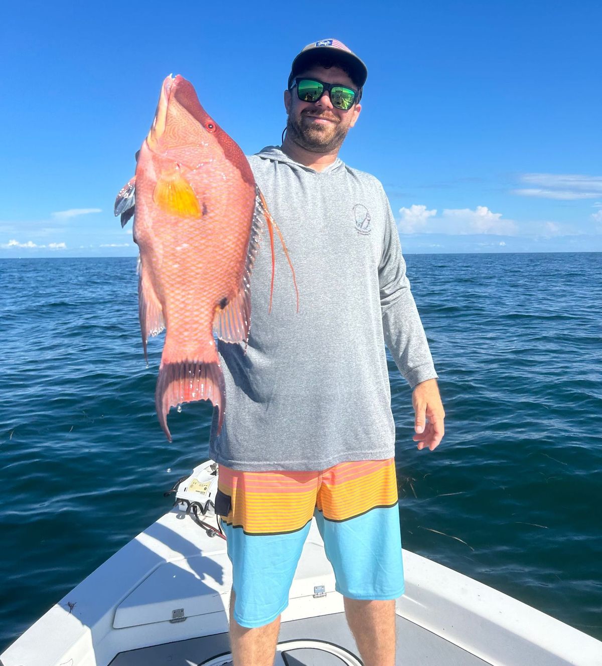 Angler holding a red grouper on the bow after a nearshore Gulf trip