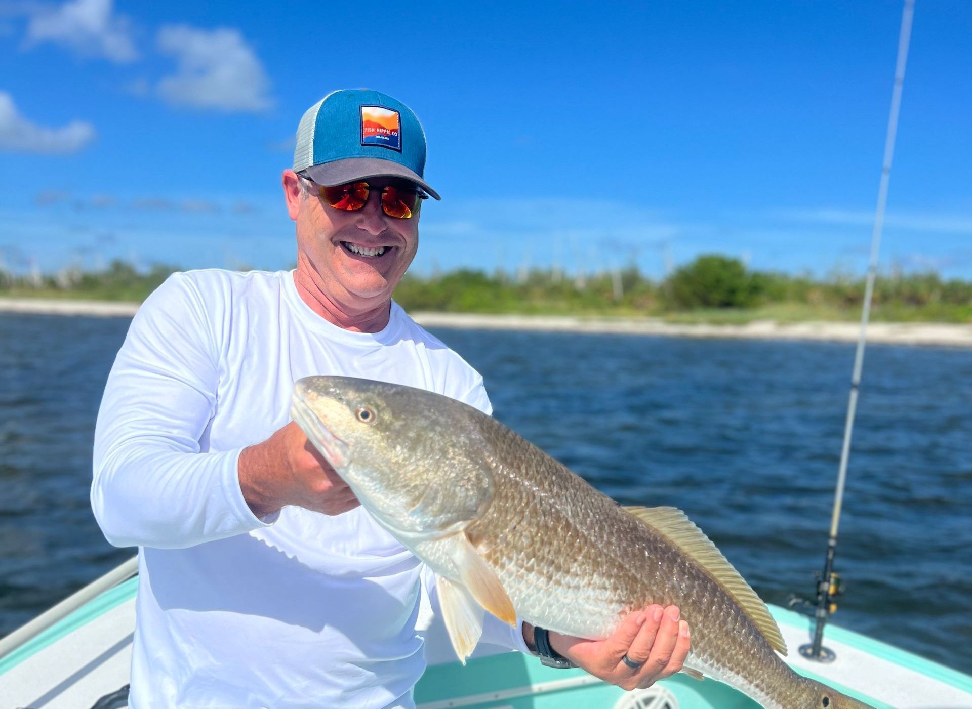 Angler holding a bull redfish along a mangrove shoreline in Tampa Bay