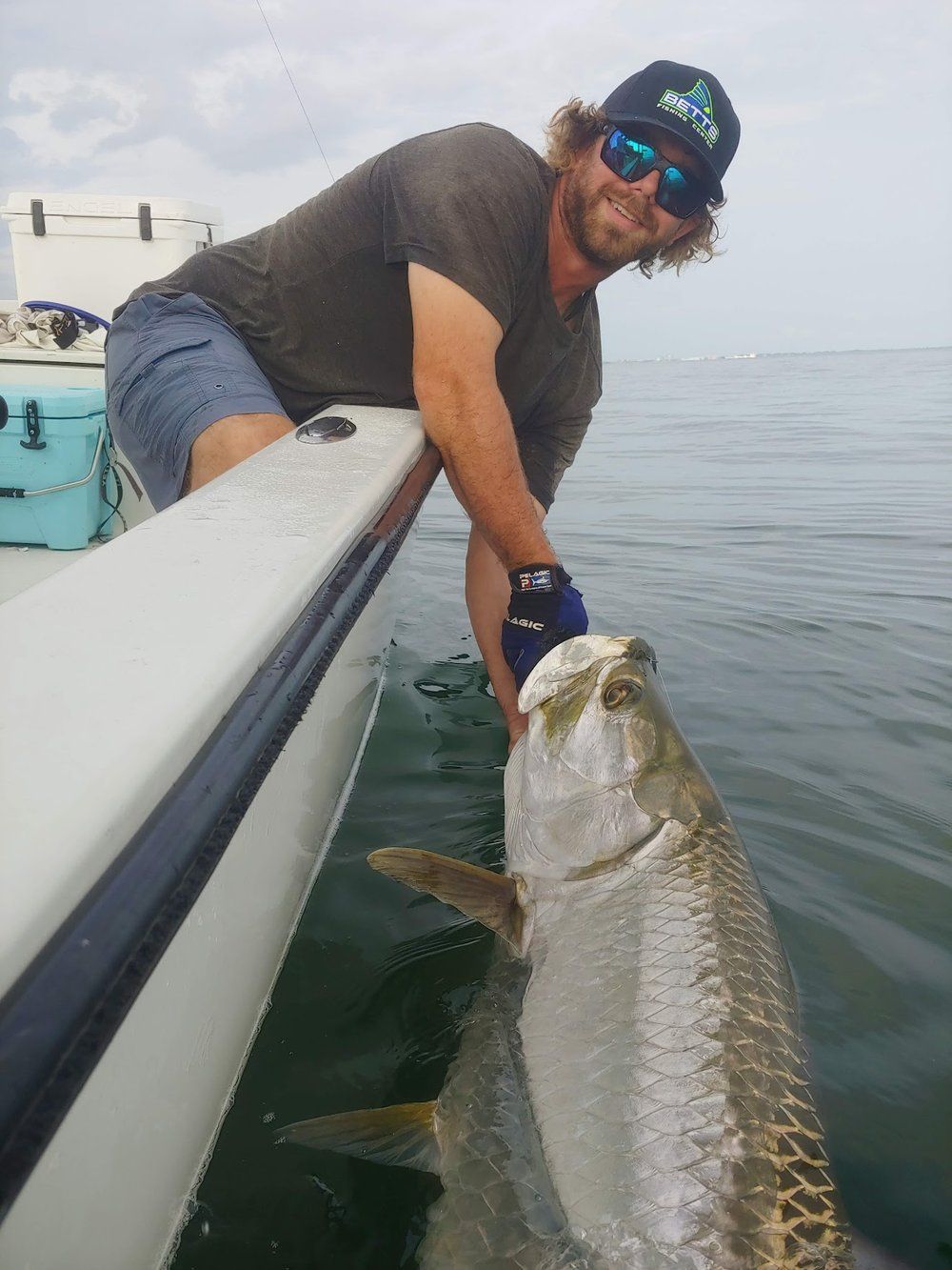 Captain Bryan leaning over the gunwale to release a tarpon