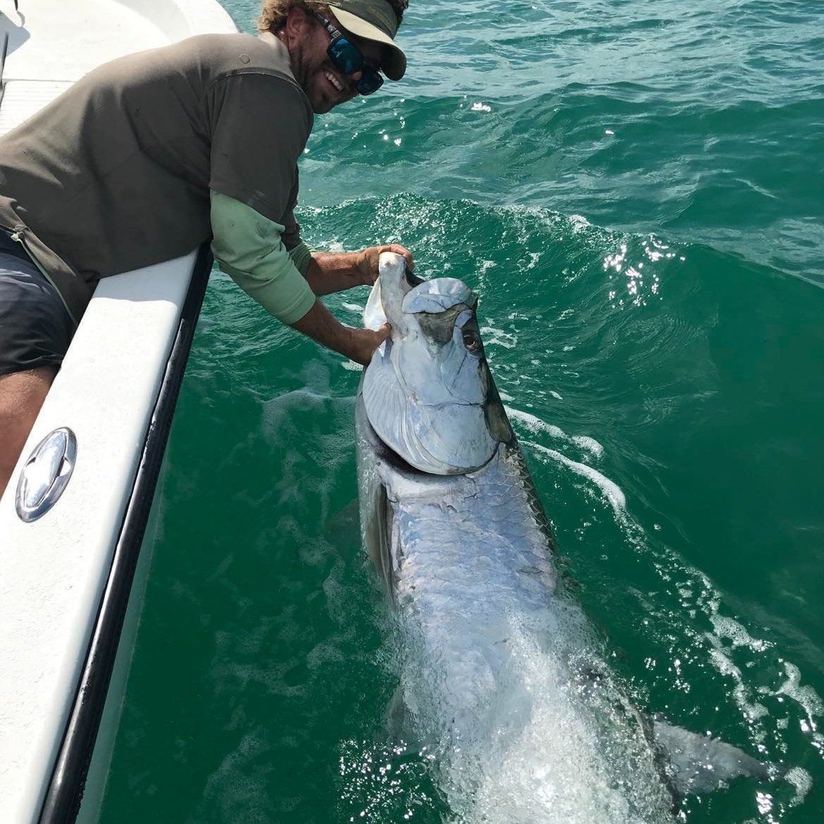 Captain Bryan leadering a tarpon alongside the boat before release