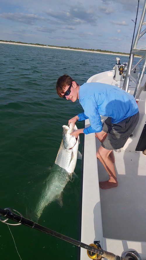 Angler releasing a tarpon over the side of the boat