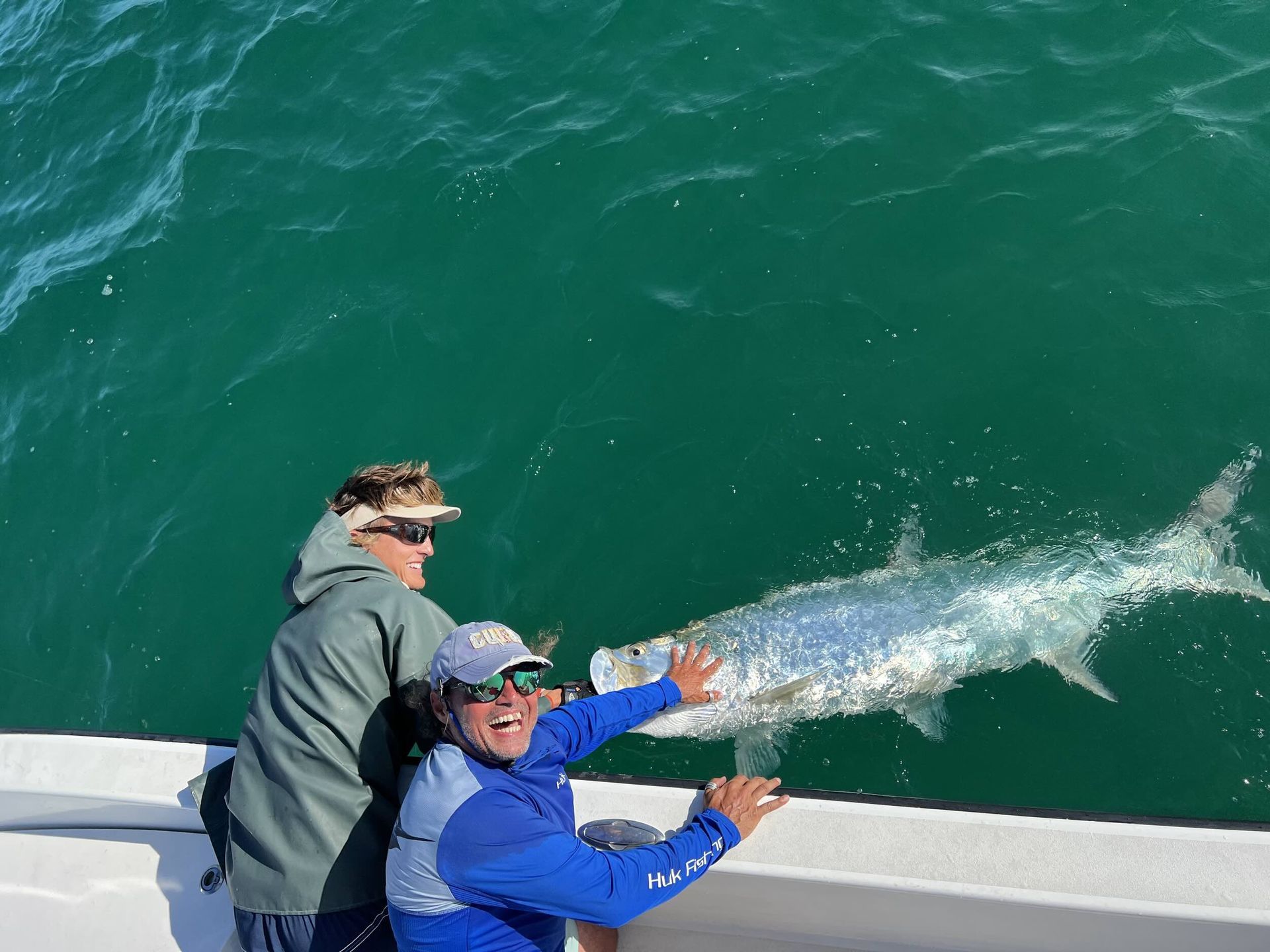 Two anglers easing a tarpon back into the green water off Saint Petersburg